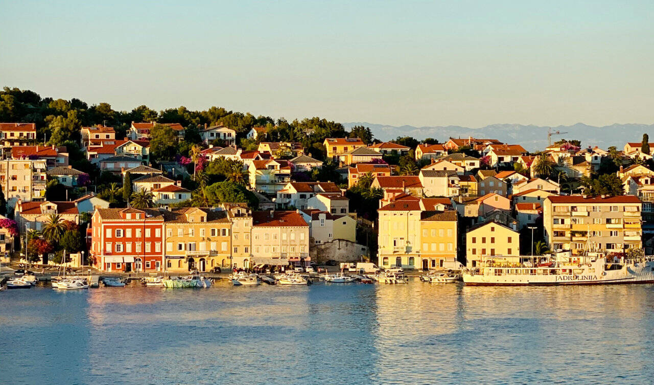 Widok na naturalny port wyspy Mali Losinj w Chorwacji. W tle widać góry chorwackiego lądu stałego.